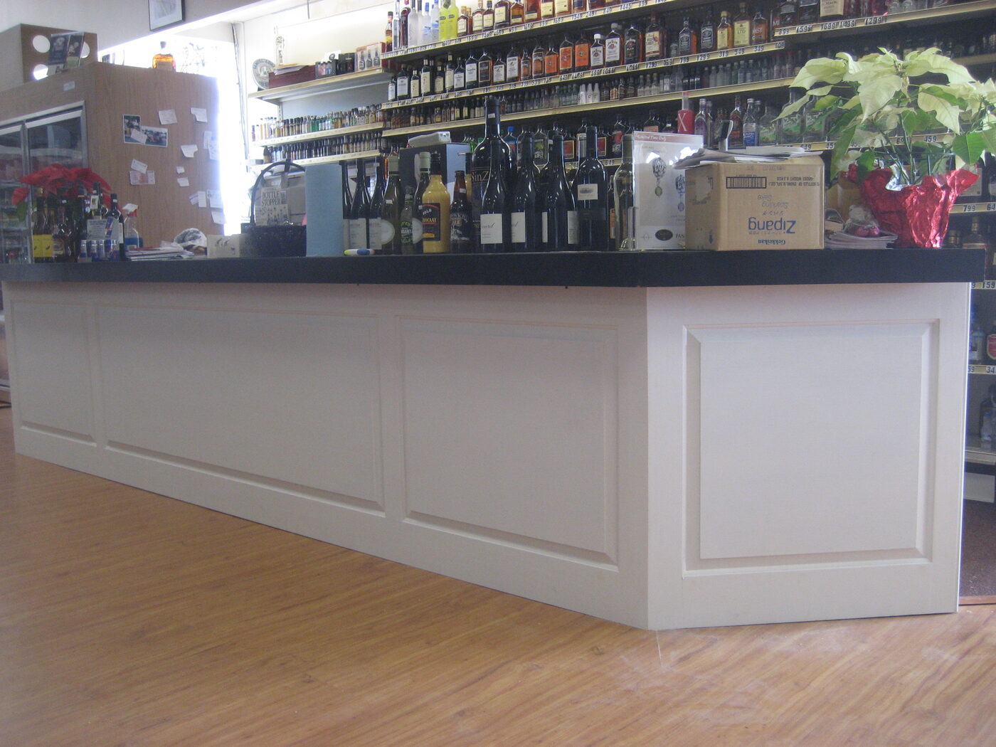 Long white raised-panel bar counter with black top, installed in wine store