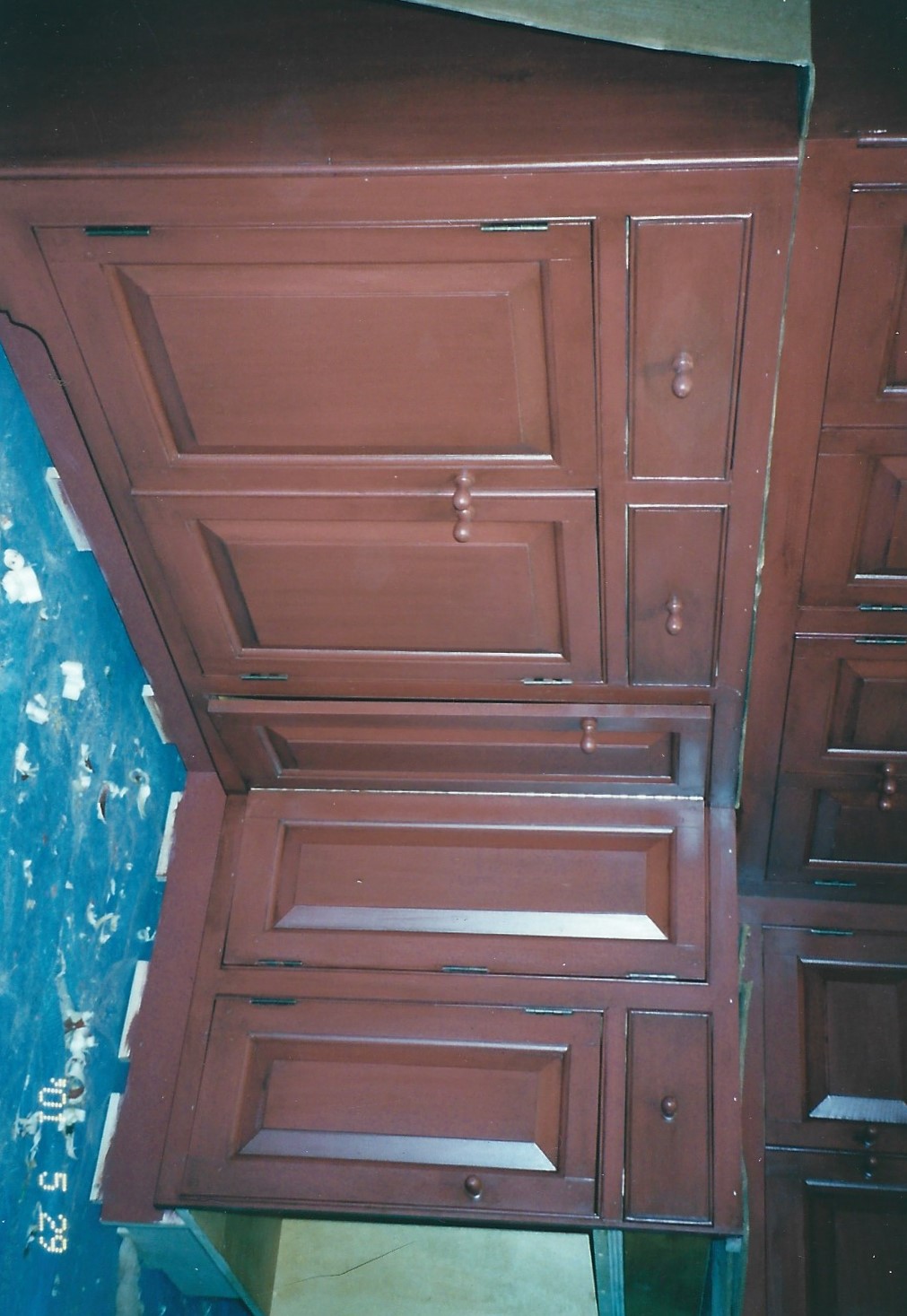 Dark red corner base cabinet run with drawers and raised panel doors