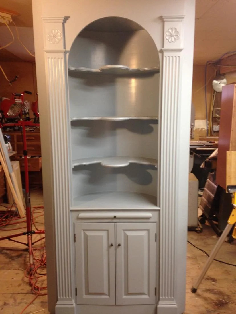 Corner cupboard installed with open upper shelves, closed lower cabinets, painted grey