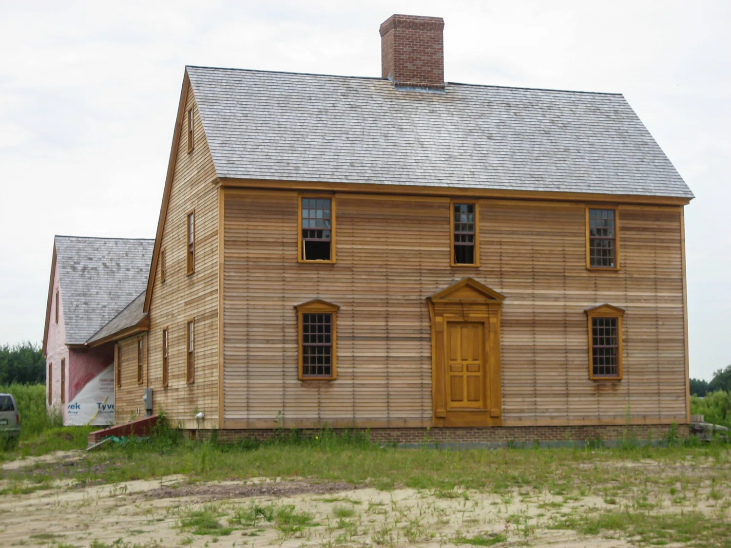 Period colonial home exterior with completed triangular pediment entryway, natural cedar siding