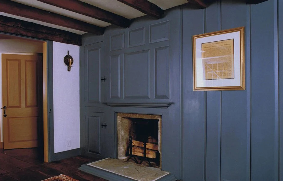 Colonial room with pink painted full-wall paneling and fireplace