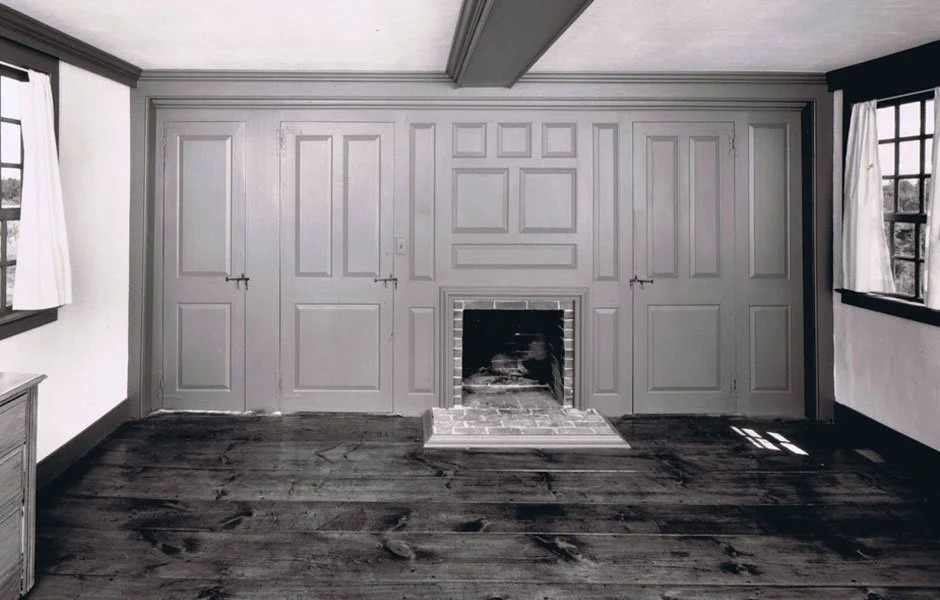 Dark wood full-height paneling in period interior with wide-plank floor