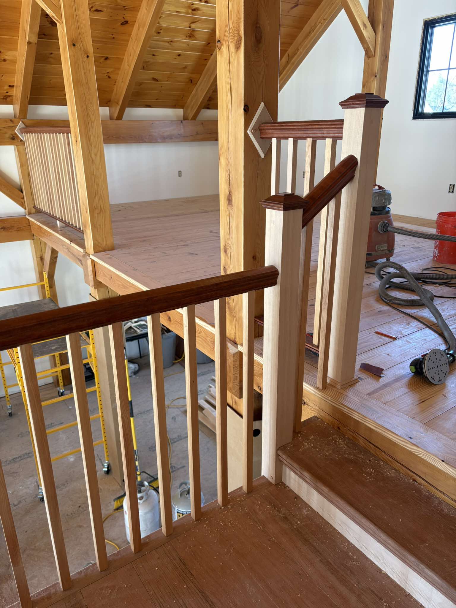 Landing view of completed staircase with dark treads and wood-paneled walls
